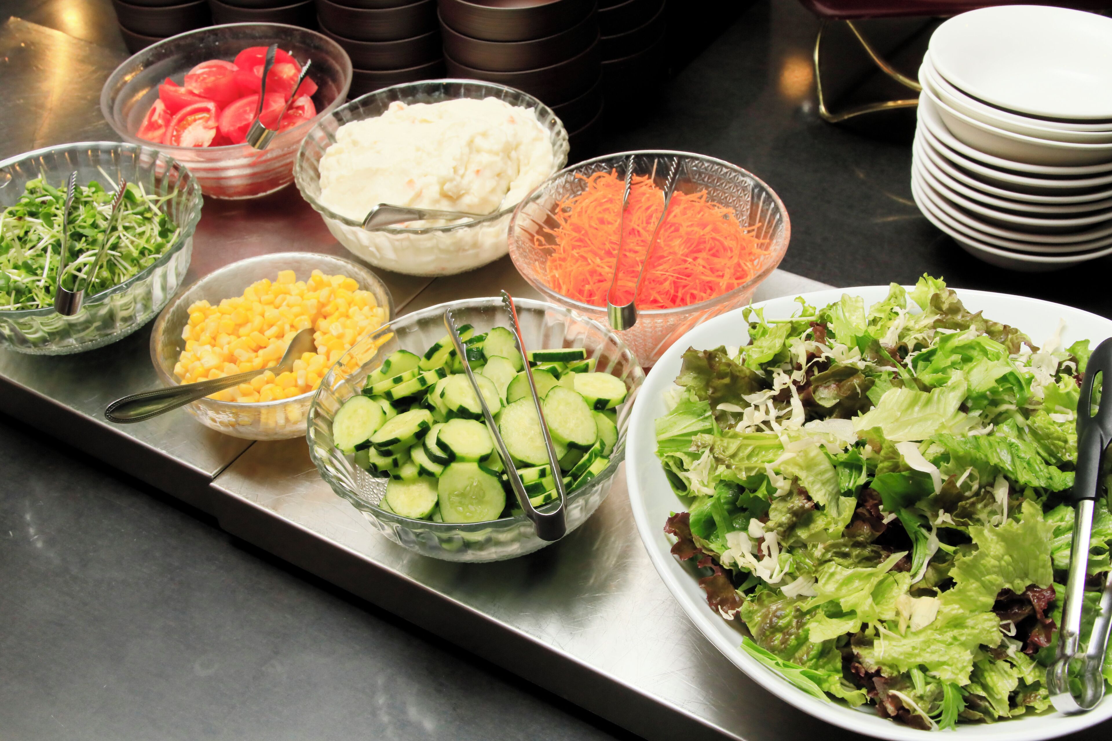 Een buffet met diverse gerechten, waaronder salades, groenten en kaas.
