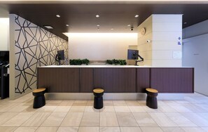 A modern reception area with a geometric wall pattern, a reception desk, a clock, and a private parking sign.