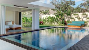 Ein modernes Hotelzimmer mit Glaswand, Pool und Blick auf den Garten.