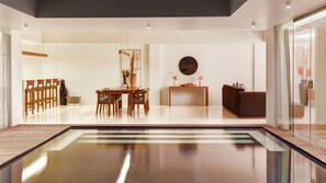 A modern interior with a dining area, a sofa, and a glass partition. - One Eleven Haven (Keroboken Kelod)