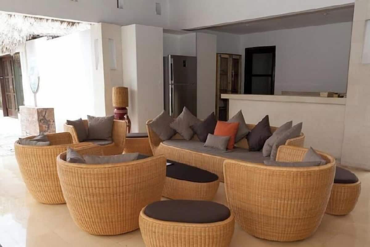 A modern living area with wicker furniture, a built-in kitchen, and a large window.