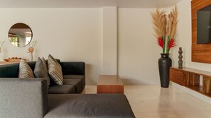 Un salon moderne comprenant un canapé, une table basse, un miroir et un vase orné de plantes décoratives.