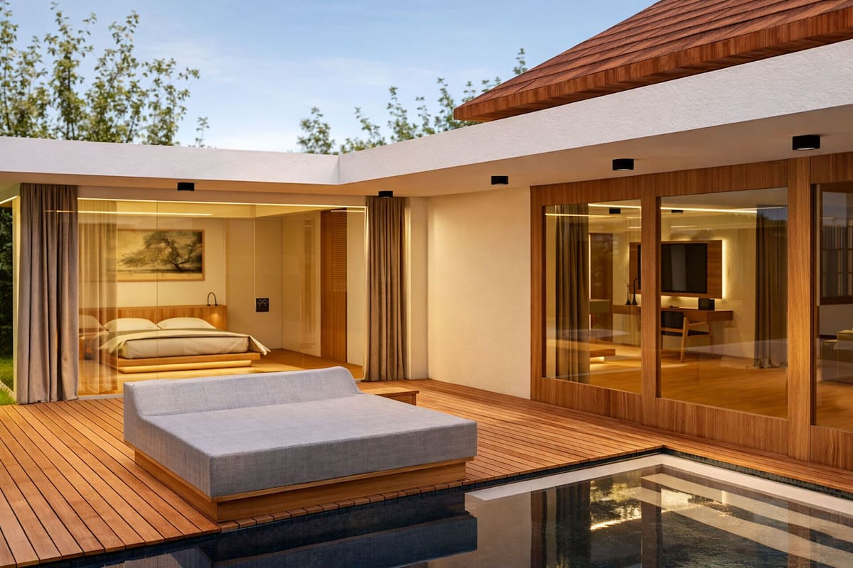 A modern bedroom with a bed, a small seating area, and a glass-enclosed bathroom.