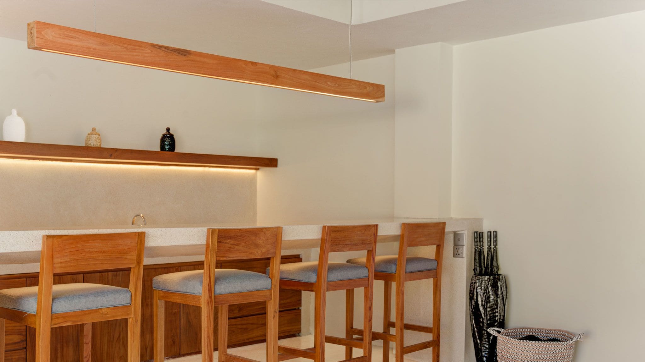 A modern bar area with wooden chairs and a long wooden shelf above the bar.