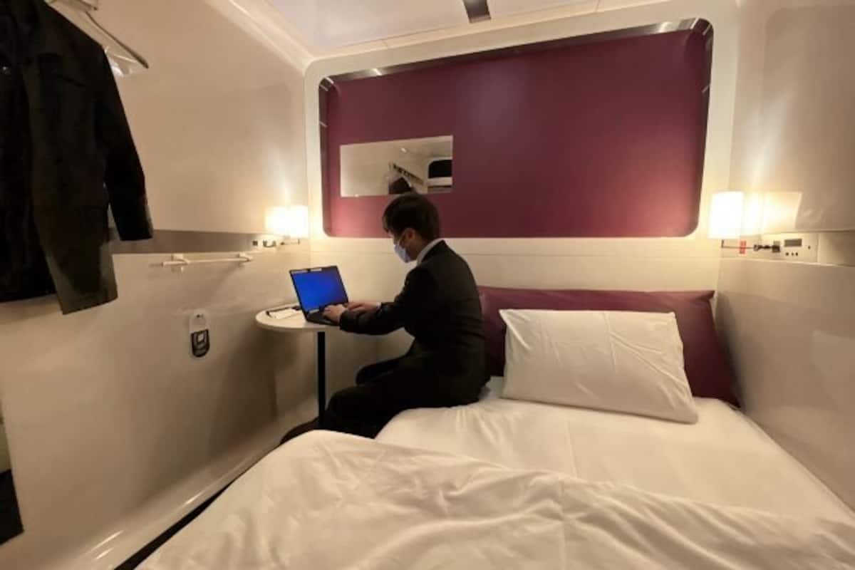 A small, private room with a bed, a laptop, a small table, and a mirror.