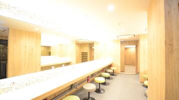 A public restroom with a long counter, multiple sinks, and several stools.