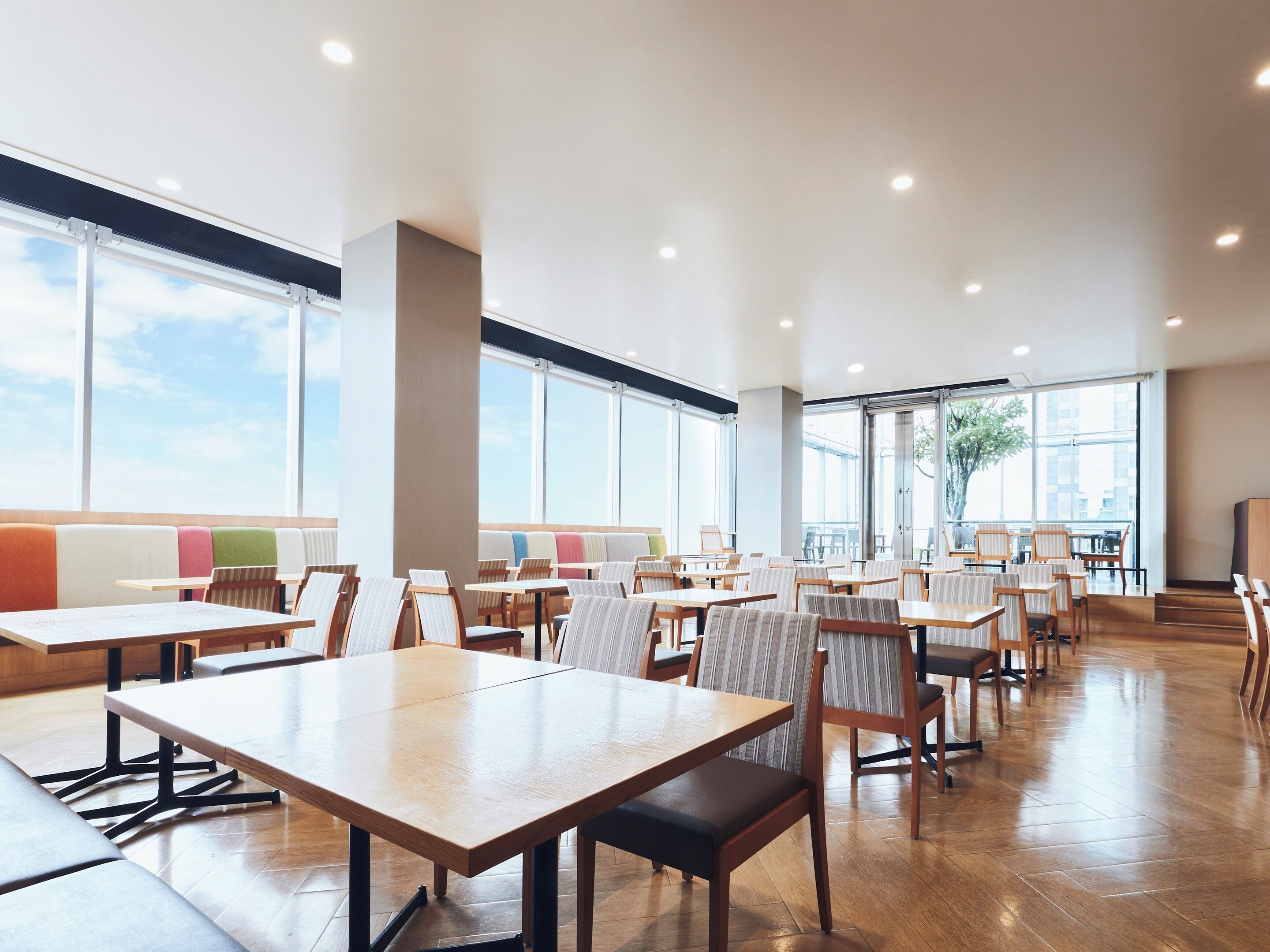A spacious indoor area with multiple tables and chairs, large windows, and a modern design.