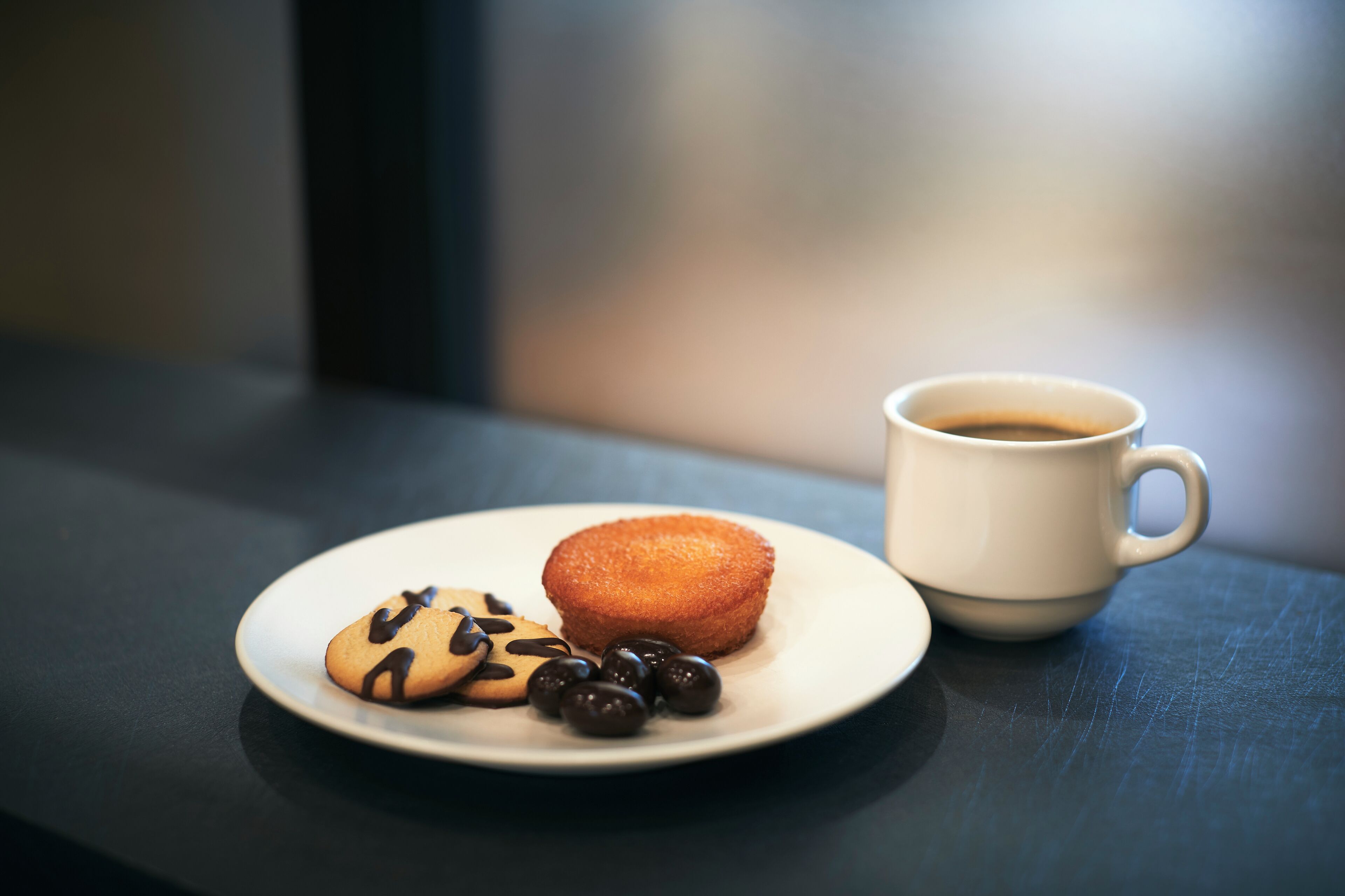 A plate with a cookie and chocolate chips, and a cup of coffee on a table.