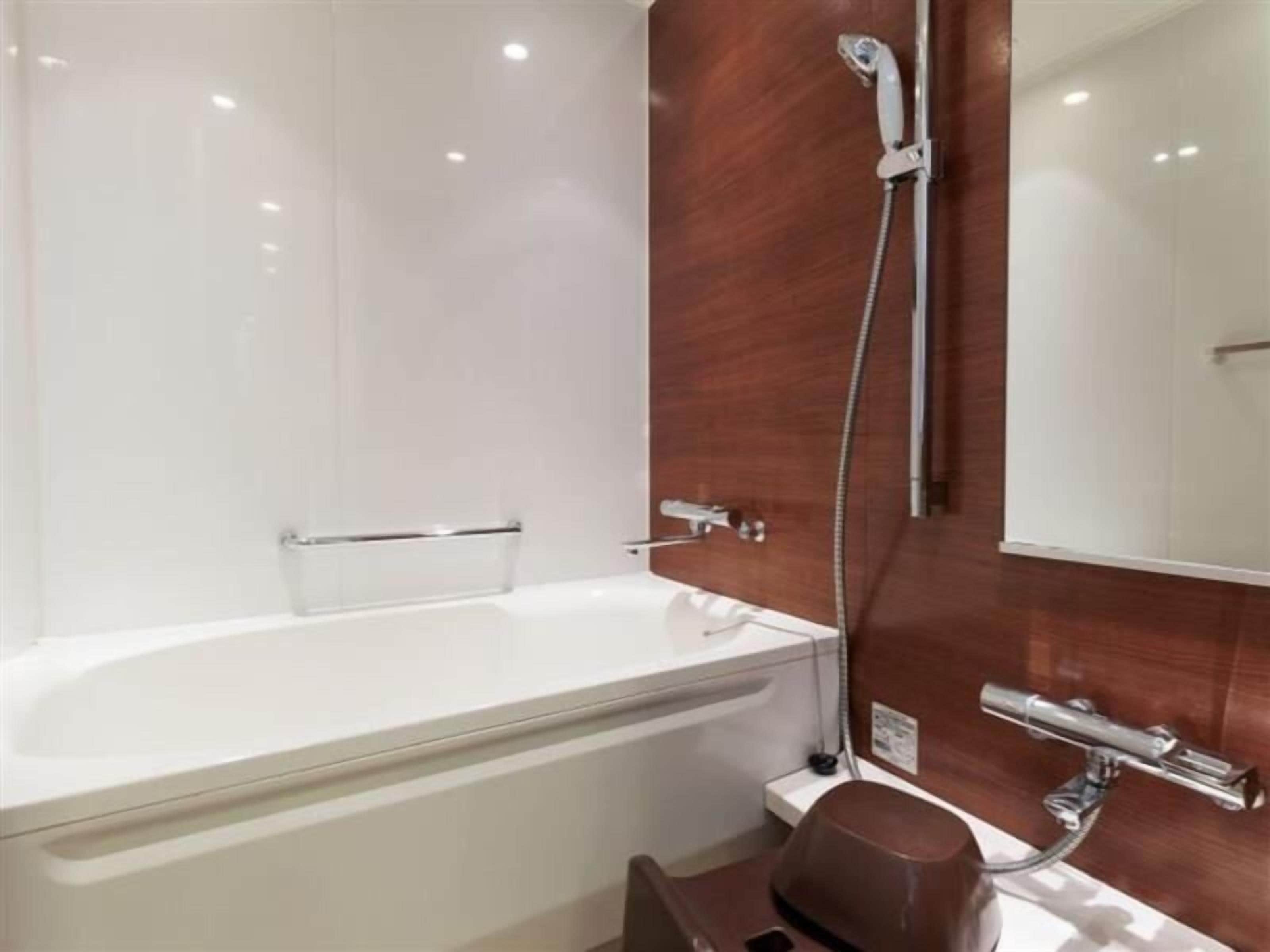 A modern bathroom with a white bathtub, a wooden vanity, and a large mirror.