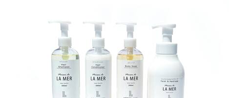 Four bottles of Maison de LA MER products: Hair Shampoo, Hair Conditioner, Body Soap, and Facial & Hand Soap.
