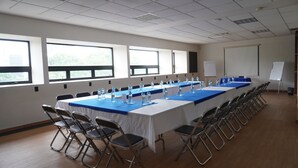 Une salle de conférence avec une longue table, des chaises et un tableau blanc.
