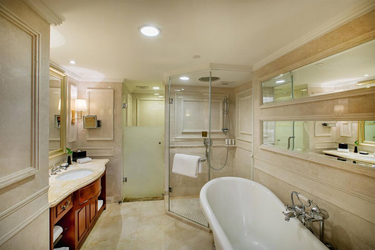 Ein luxuriöses Badezimmer mit einer freistehenden Badewanne, einer Glaskabine zur Dusche und einem Waschtisch mit Marmorplatte.