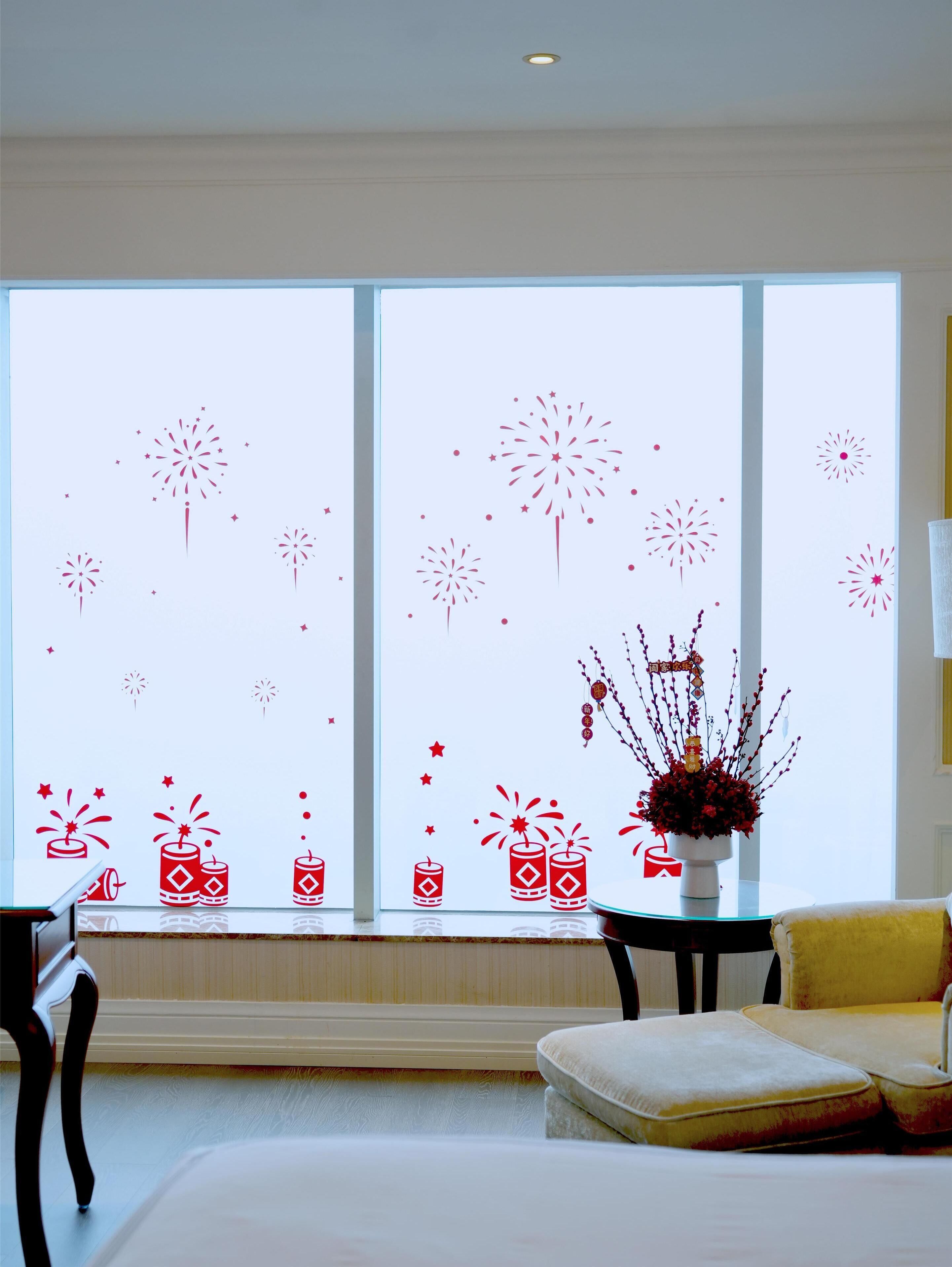 Una habitación con un ventanal amplio decorada con adornos navideños rojos, una mesita con un jarrón de flores rojas y un sillón amarillo.