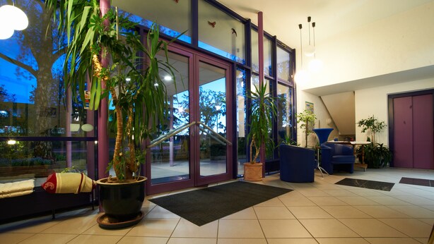 Um interior moderno com grandes portas de vidro, plantas em vasos e um espaço de estar.