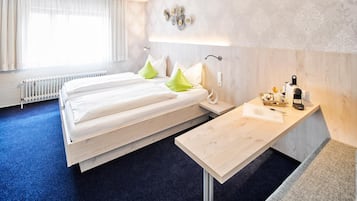 A hotel room with a bed, bedside table, and a small desk with a chair.
