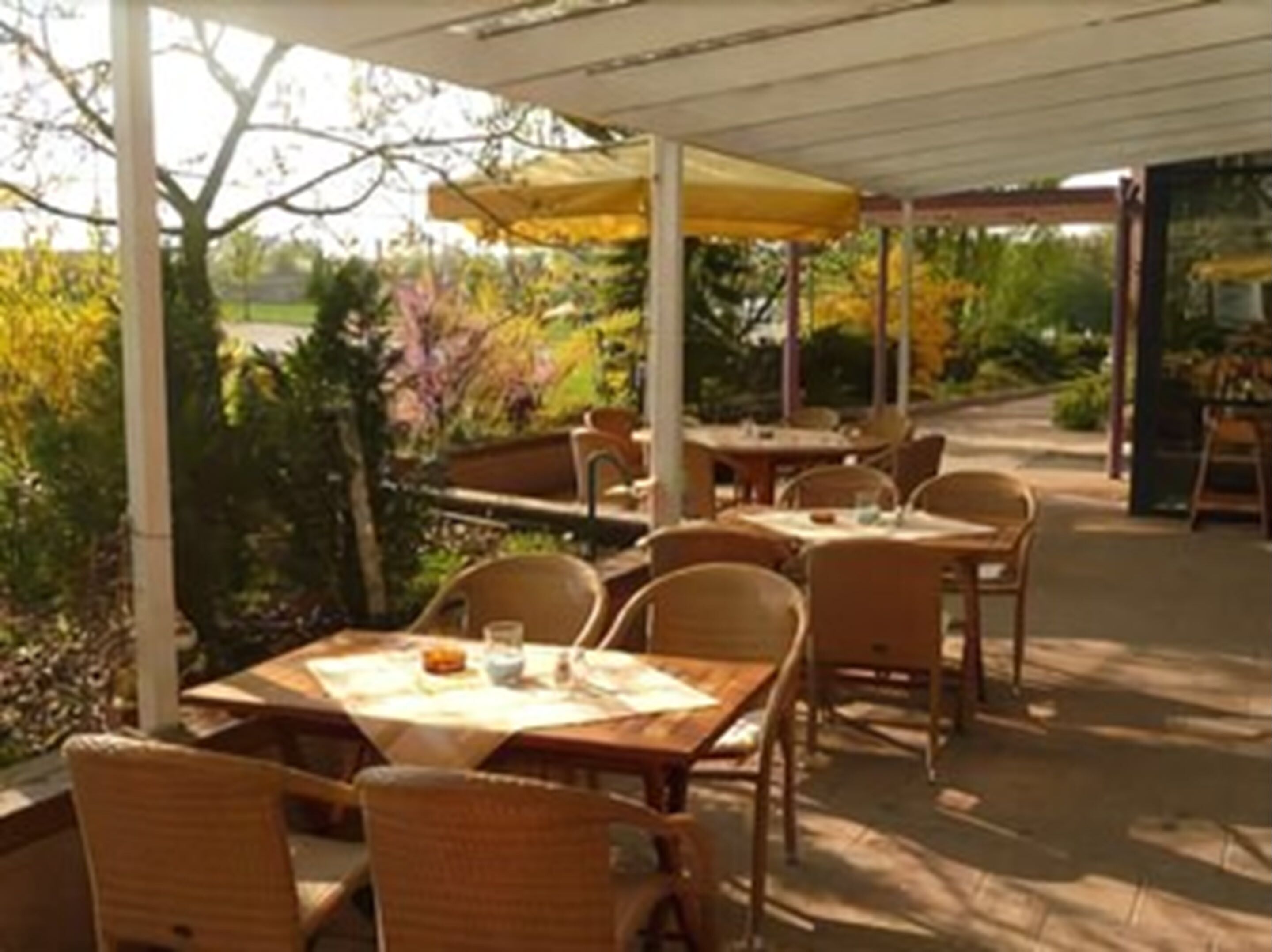 An outdoor patio with tables and chairs, covered by a white canopy.
