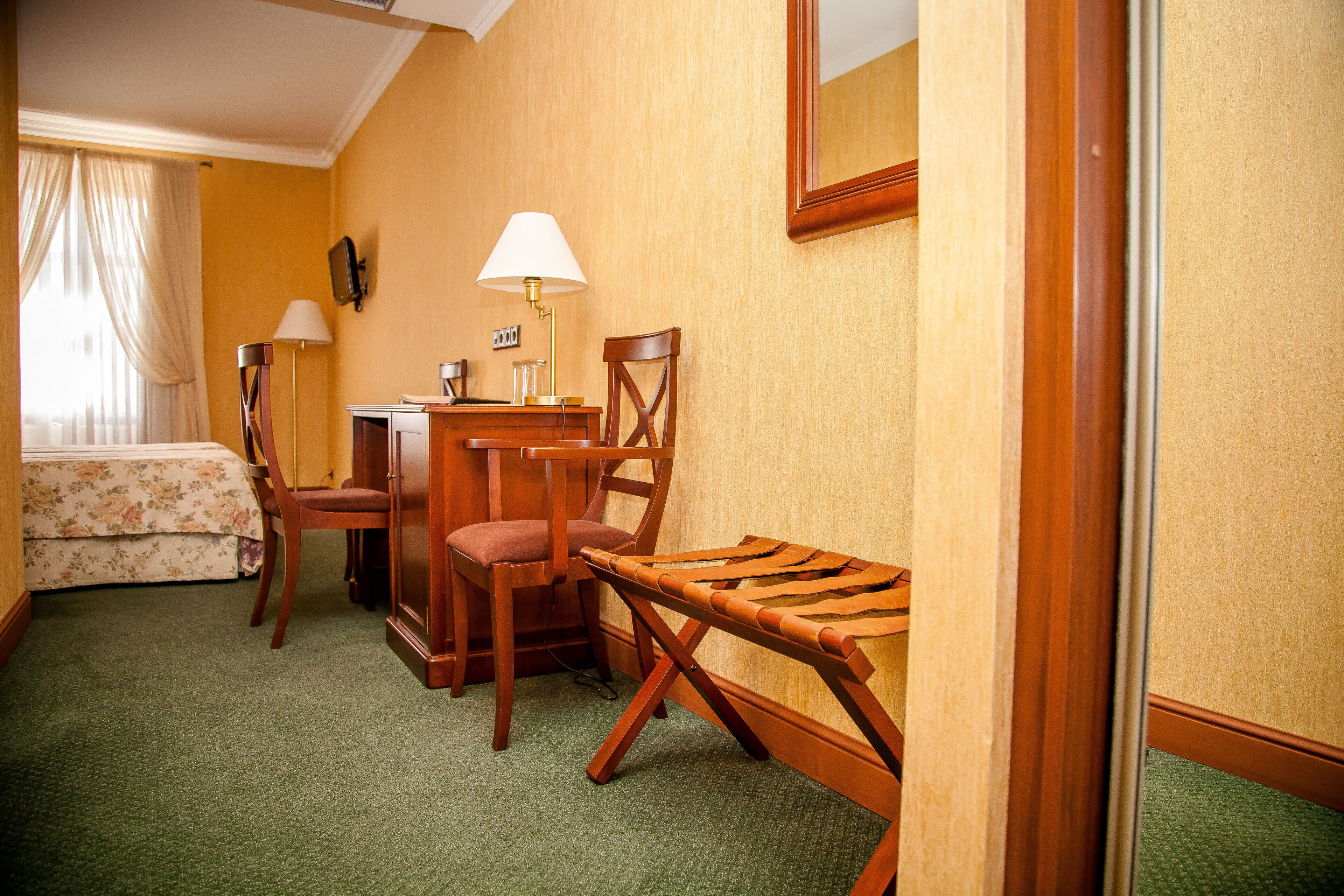 Une chambre d’hôtel avec un lit, deux chaises, un bureau, une lampe et un miroir.