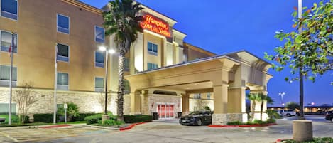 A hotel with a prominent sign, a covered entrance, and a parking lot.