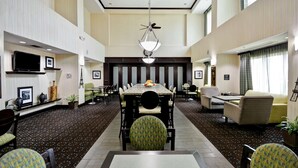 Eine geräumige Hotelhalle mit einem zentralen Esstisch, verschiedenen Sitzbereichen und einem Deckenventilator.