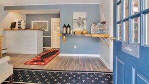 Une salle d’attente avec un comptoir, une porte bleue portant l’inscription « Bureau », et une étagère fixée au mur où sont disposés divers objets.
