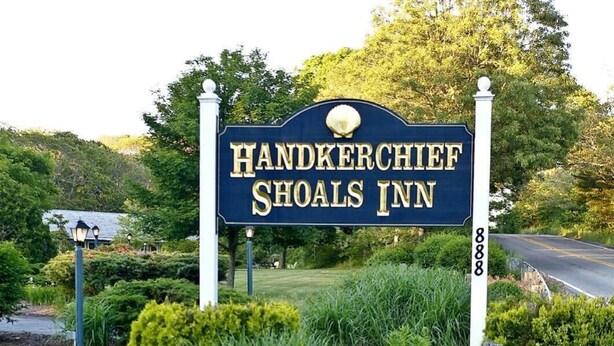 Une enseigne indiquant l’emplacement de l’auberge Handkerchief Shoals, avec un jardin bien entretenu au premier plan.