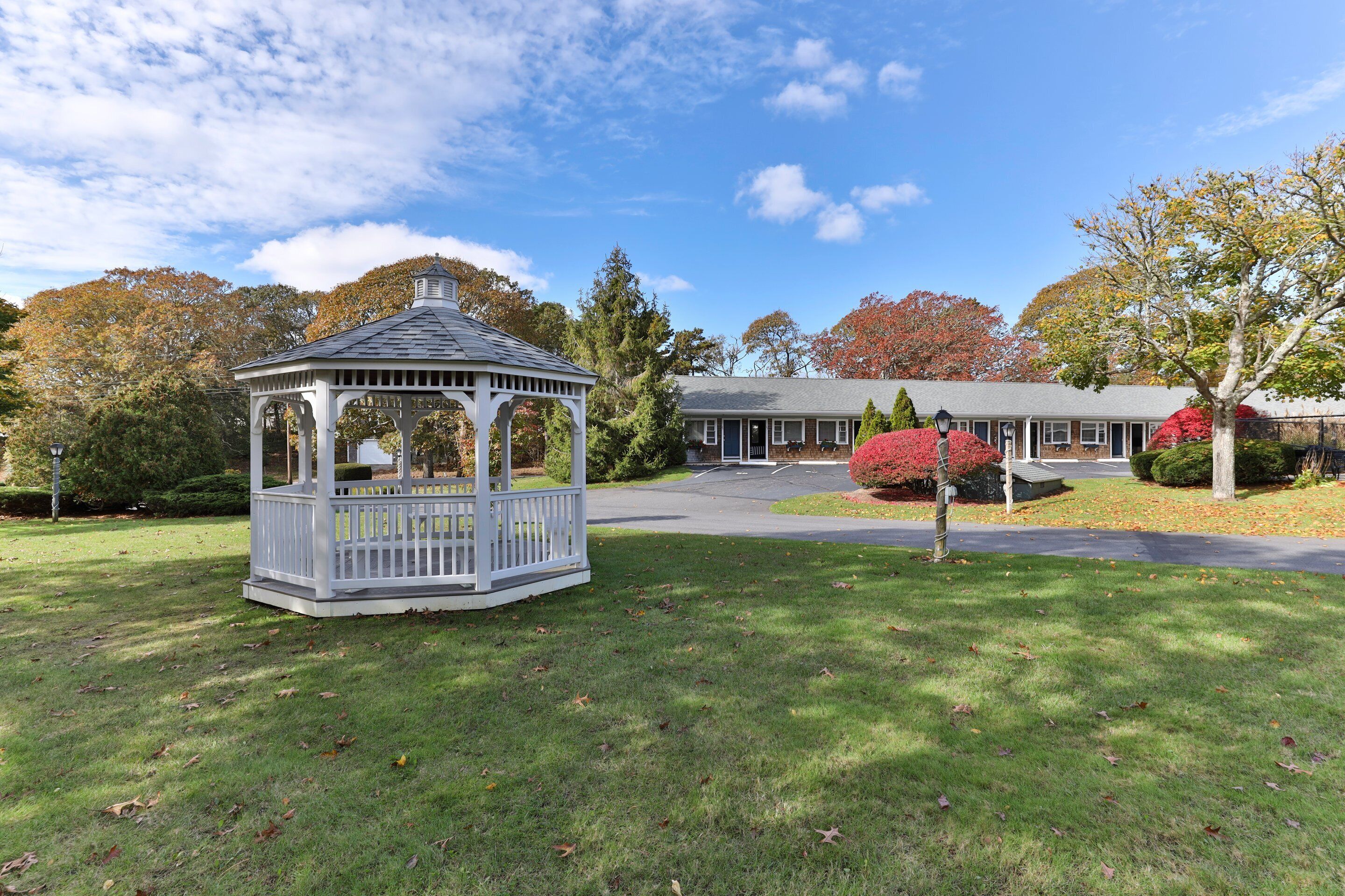 A gazebo in a well-maintained lawn area with a house in the background.