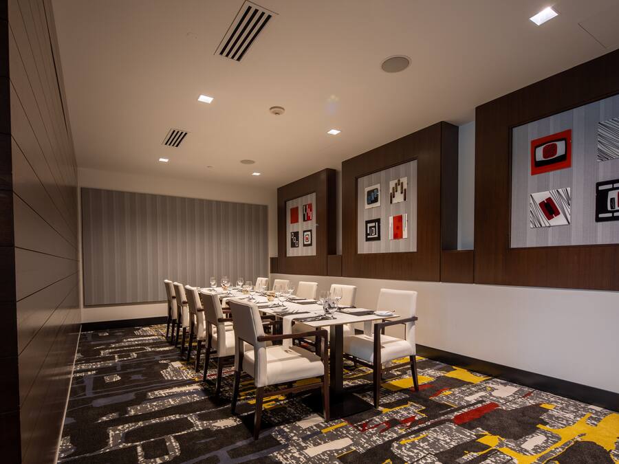 A conference room with a long table, white chairs, and a patterned carpet.