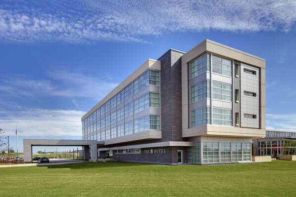 A modern hotel with a flat roof, large windows, and a well-maintained lawn.