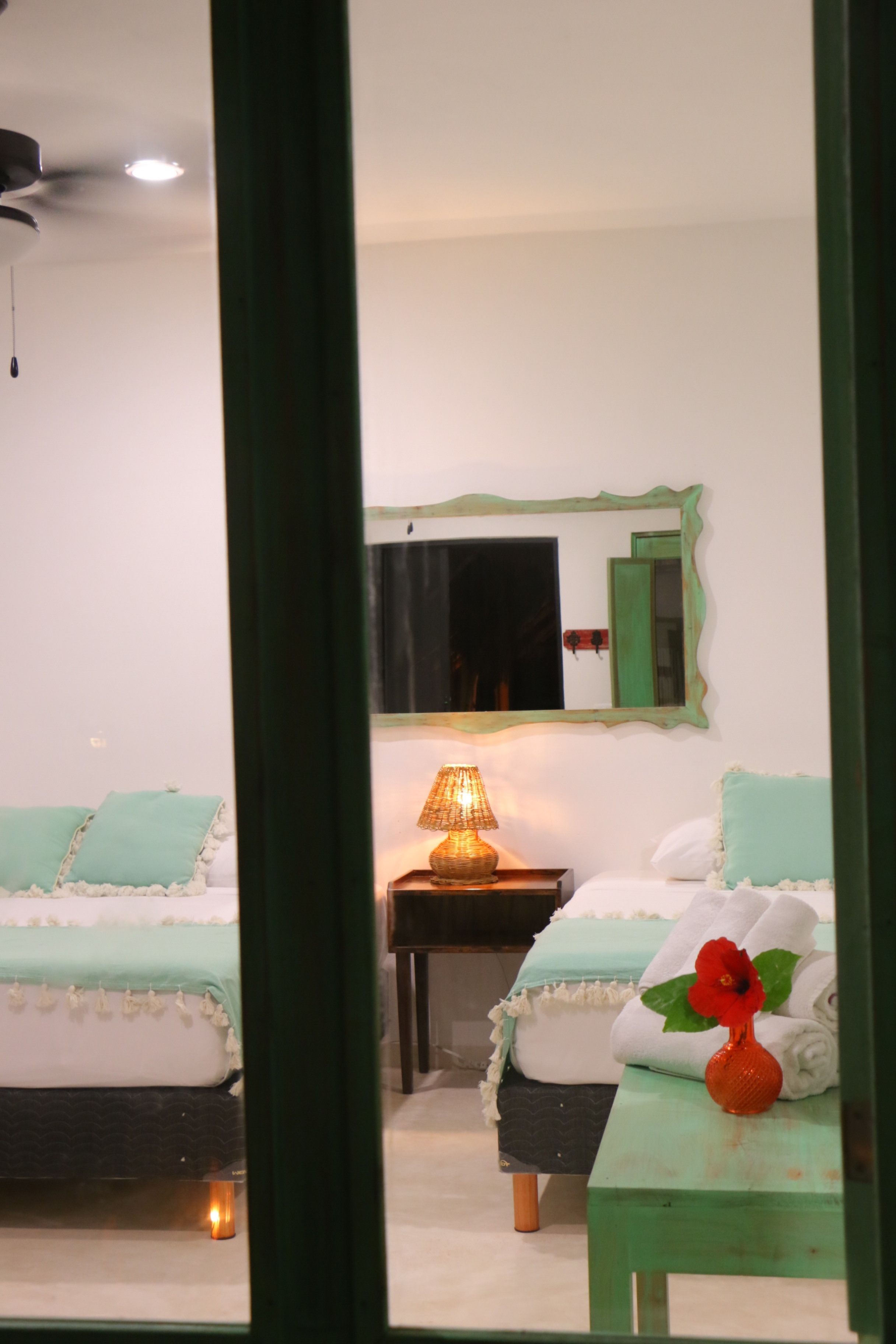 Un dormitorio con dos camas, una mesita de noche con lámpara y un espejo en la pared.