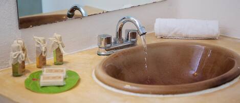 A bathroom sink with a brown basin, a mirror above it, and a towel hanging on the wall.