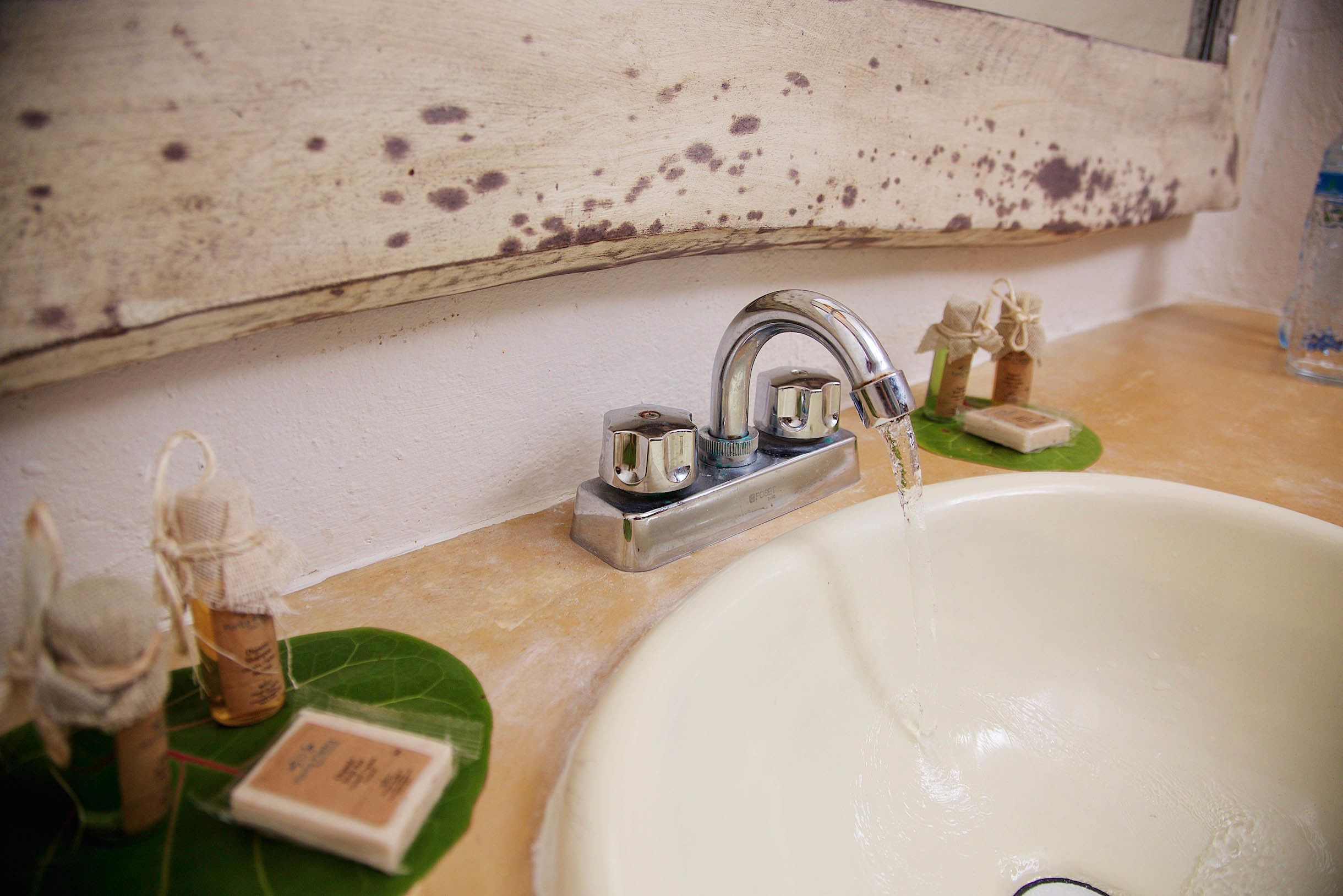 A bathroom sink with a wooden shelf above it.