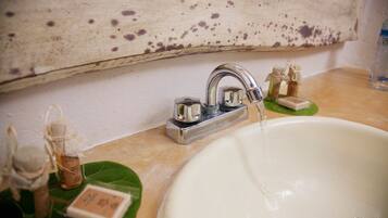 A bathroom sink with a wooden shelf above it.