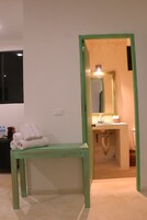 Une salle de bain avec un miroir encadré de vert, un lavabo et un banc avec des serviettes.