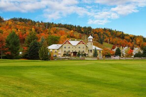 A large building with a clock tower, surrounded by a well-maintained lawn and autumn-colored trees. - Calabogie Peaks Resort, an Ascend Collection Hotel (Greater Madawaska)