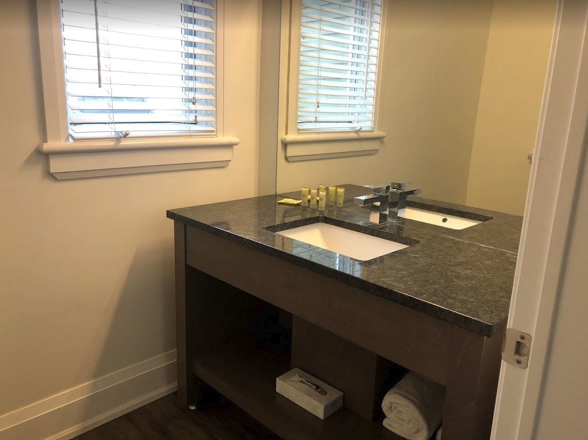A bathroom with a dark granite countertop, two sinks, and a mirror above.