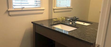A bathroom with a dark granite countertop, two sinks, and a mirror above.
