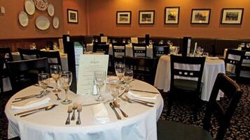 A restaurant with round tables set for dining, featuring menus and wine glasses.