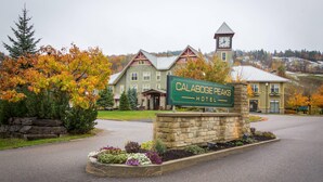 Une enseigne d’hôtel sur laquelle on peut lire « Calabogie Peaks Hotel », un bâtiment en pierre doté d’un clocher et des arbres aux couleurs automnales.