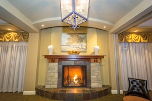 A fireplace with a stone surround, a chandelier, and a painting above it. - Calabogie Peaks Resort, an Ascend Collection Hotel (Greater Madawaska)