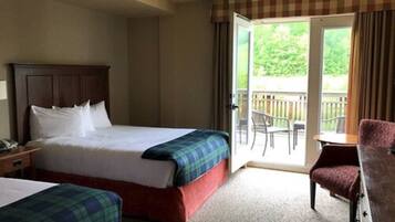 A hotel room with a bed, a chair, and a balcony with a view of greenery.