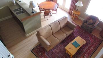 A living room with a sofa, a small wooden table, a patterned rug, and a dining area with a table and chairs.