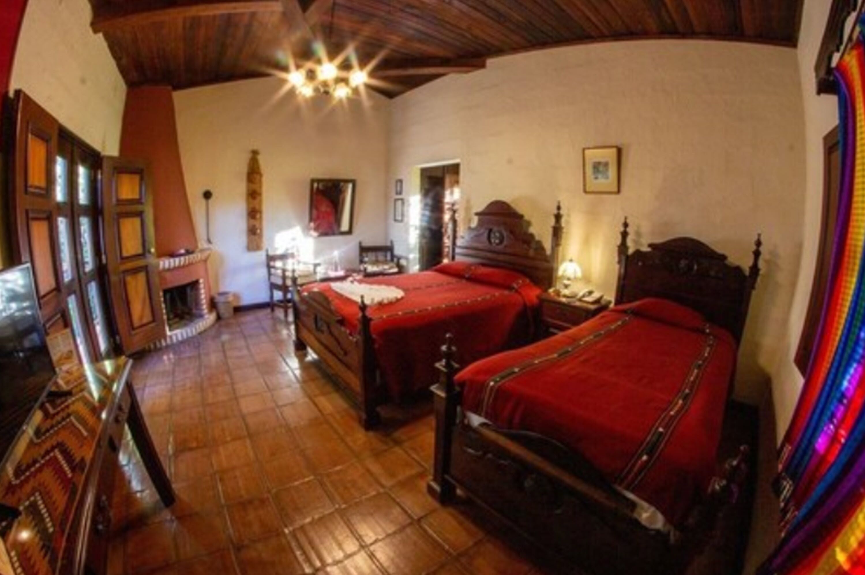 A traditional room with two wooden beds, a wooden floor, and a fireplace.