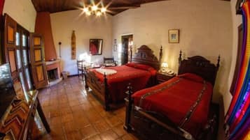 A traditional room with two wooden beds, a wooden floor, and a fireplace.