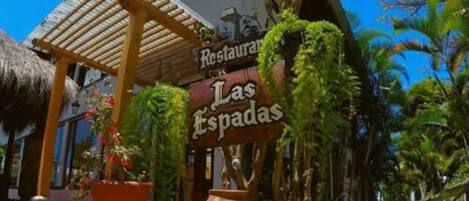 Un restaurant appelé « Las Espadas », doté d’une pergola rustique en bois et agrémenté de plantes en pot.