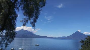 A calm lake with boats, surrounded by mountains and trees.