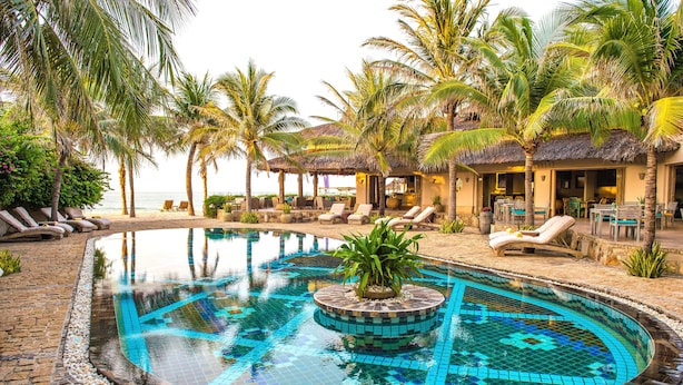 A swimming pool with a mosaic design, surrounded by lounge chairs and palm trees. - Sailing Club Resort Mui Ne (Mui Ne)
