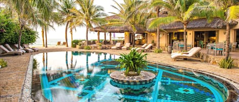 Alberca al aire libre, sombrillas en la alberca y camastros