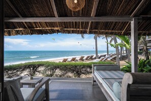 A beachside lounge with a view of the ocean, lounge chairs, and a thatched roof structure. - Sailing Club Resort Mui Ne (Mui Ne)