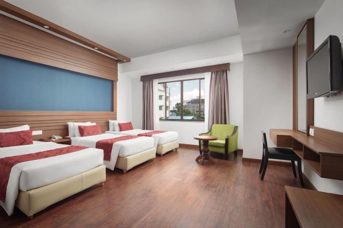 Une chambre d’hôtel avec deux lits, un bureau, une chaise et un téléviseur.