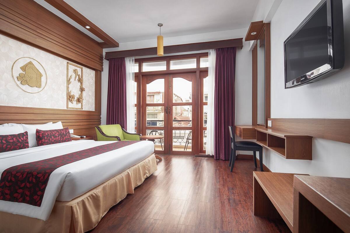 Ett hotellrum med en stor säng, ett skrivbord, en stol och en tv.